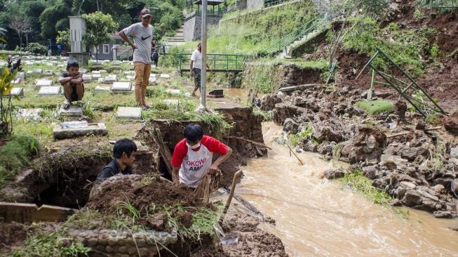 Petugas membersihkan sejumlah makam yang rusak terdampak longsor terbing di TPU Cikutra, Bandung, Jawa Barat, Sabtu (2/5). [ANTARA FOTO/Novrian Arbi]