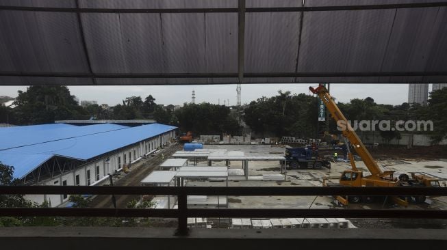 Pekerja dibantu alat berat menyelesaikan proyek rumah sakit rujukan virus Corona di kompleks Universitas Pertamina, Simprug, Jakarta, Sabtu (2/5).  [Suara.com/Angga Budhiyanto]  