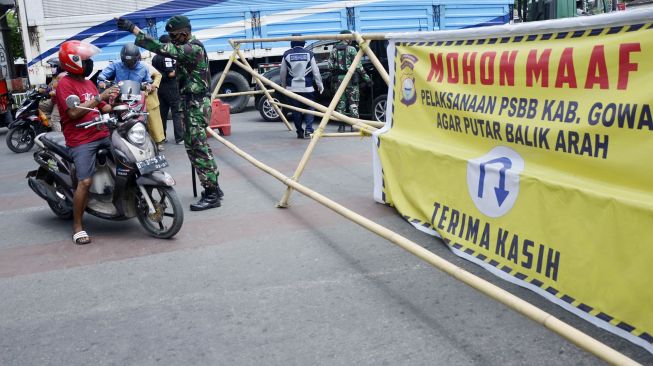 Personel TNI memeriksa sejumlah pengendara motor yang akan melewati titik pemeriksaan di perbatasan Kabupaten Gowa dan Makassar, Sulawesi Selatan, Senin (4/5). [ANTARA FOTO/Abriawan Abhe]