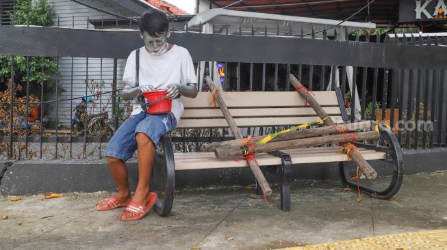 Pengamen menghitung uang di bangku trotoar yang disegel di Rawamangun, Jakarta Timur, Senin (4/5). [Suara.com/Alfian Winanto]