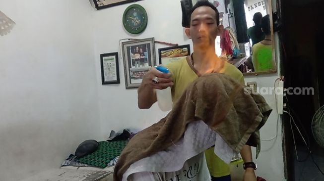 Muhammad Safari a.k.a Kenyo, pemijat metode api di Kenyo Style, Jalan Kebon Baru Nomor 27 RT2/RW6 Tebet, Jakarta Selatan, yang bertahan di tengah kelesuan ekonomi akibat wabah virus corona. [Suara.com/Yosea Arga Pramudita]