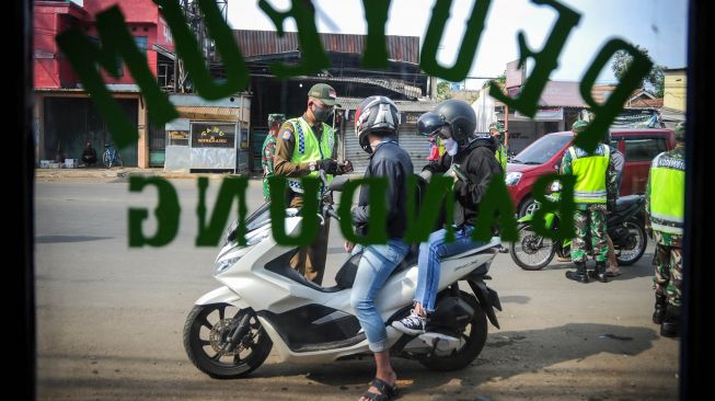 Petugas memberhentikan kendaraan bermotor di titik pemeriksaan Pembatasan Sosial Berskala Besar (PSBB) di Jatinangor, perbatasan Kabupaten Bandung dan Kabupaten Sumedang, Jawa Barat, Rabu (6/5).  [ANTARA FOTO/Raisan Al Farisi]
