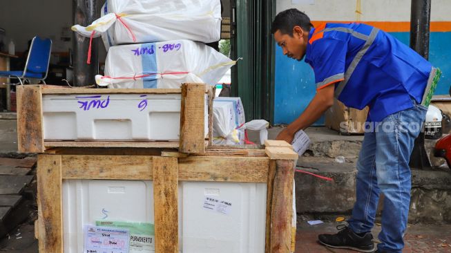 Petugas  ekspedisi melabeli paket barang di Pasar Senen, Jakarta Pusat, Rabu (6/5). [Suara.com/Alfian Winanto]