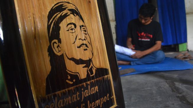 Anang Setyo Pambudi menyelesaikan ukiran pada bambu bergambar wajah almarhum Didi Kempot di Desa Sumberjo, Kabupaten Jombang, Jawa Timur, Rabu (6/5).  [ANTARA FOTO/Syaiful Arif]