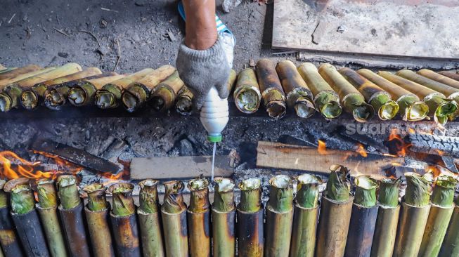 Pekerja memasukan santan kedalam lemang di Kramat Raya, Senen, Jakarta Pusat, Rabu (6/5). [Suara.com/Alfian Winanto]