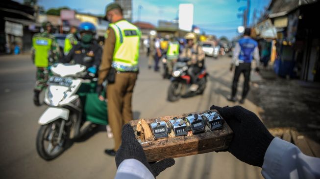 Petugas menghitung jumlah kendaraan yang melintas di titik pemeriksaan Pembatasan Sosial Berskala Besar (PSBB) di Jatinangor, perbatasan Kabupaten Bandung dan Kabupaten Sumedang, Jawa Barat, Rabu (6/5).  [ANTARA FOTO/Raisan Al Farisi]
