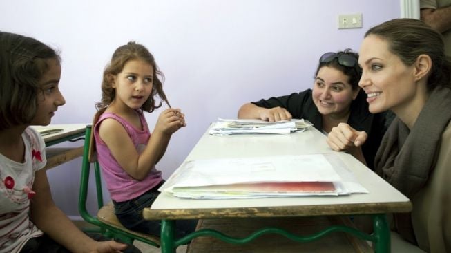 Aktris Angelina Jolie (kanan) yang menjadi utusan khusus UNHCR, didampingi perwakilan UNHCR, tengah berbincang dengan anak pengungsi Suriah di Bar Elias, Lembah Bekaa, Lebanon. Foto diambil pada 12 September 2012. [AFP/UNHCR]