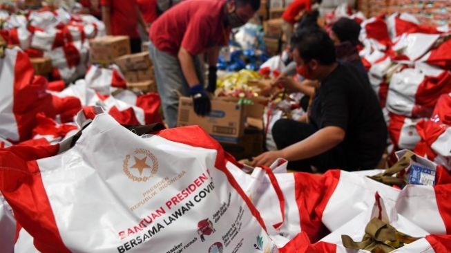 Pekerja mengemas paket bantuan sosial (bansos) di Gudang Food Station Cipinang, Jakarta, Rabu (22/4/2020). Pemerintah pusat menyalurkan paket bansos masing-masing sebesar Rp 600 ribu per bulan selama tiga bulan sebagai upaya untuk mencegah warga tidak mudik dan meningkatkan daya beli selama pandemi COVID-19 kepada warga yang membutuhkan di wilayah Jabodetabek. [ANTARA FOTO/M Risyal Hidayat]