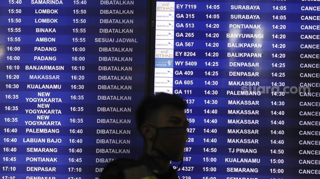 Petugas berada di depan papan informasi keberangkatan di Terminal 3 Bandara Soekarno Hatta, Tangerang, Banten, Kamis (7/5). [Suara.com/Angga Budhiyanto]