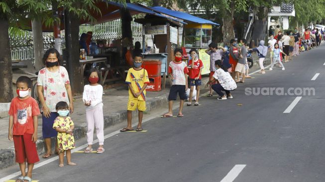 Warga mengantre dengan menerapkan aturan jarak fisik atau 'physical distancing' untuk mendapatkan takjil gratis di Jalan Cempaka Putih Tengah, Kecamatan Cempaka Putih, Jakarta Pusat, Kamis (7/5). [Suara.com/Angga Budhiyanto]