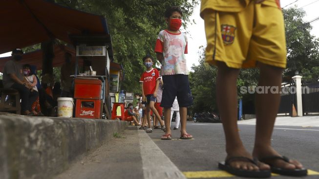 Warga mengantre dengan menerapkan aturan jarak fisik atau 'physical distancing' untuk mendapatkan takjil gratis di Jalan Cempaka Putih Tengah, Kecamatan Cempaka Putih, Jakarta Pusat, Kamis (7/5). [Suara.com/Angga Budhiyanto]