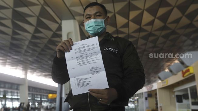 Seorang calon penumpang dengan ijin khusus kembali ke daerah asal usai menjalani pendidikan di Arab Saudi menunjukan surat syarat terbang di Terminal 3 Bandara Soekarno Hatta, Tangerang, Banten, Kamis (7/5).  [Suara.com/Angga Budhiyanto]