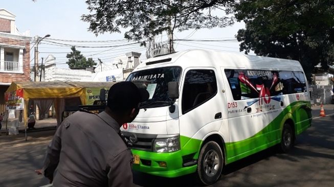 Petugas menghentikan sebuah mobil jenis elf di cek point di kawasan Jonggol, Kabupaten Bogor, Jumat (8/5/2020). (Suara.com/Bagaskara Isdiansyah)