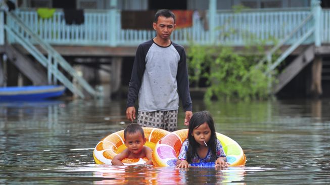 Orang tua mengajarkan anaknya berenang saat banjir luapan Sungai Batanghari merendam kawasan permukiman di Mudung Laut, Pelayangan, Jambi, Jumat [ANTARA FOTO/Wahdi Septiawan]