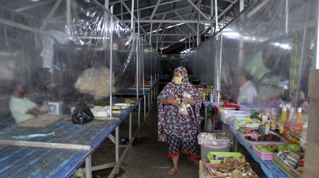 Pembeli berbelanja dengan sekat tirai pelindung plastik pada kios jualan di Pasar Kaget Borong Indah, Makassar, Sulawesi Selatan, Sabtu (9/5). [ANTARA FOTO/Arnas Padda]