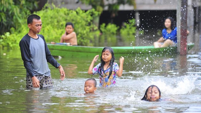 Orang tua mengajarkan anaknya berenang saat banjir luapan Sungai Batanghari merendam kawasan permukiman di Mudung Laut, Pelayangan, Jambi, Jumat [ANTARA FOTO/Wahdi Septiawan]