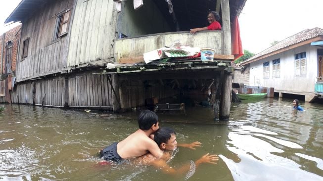 Orang tua mengajarkan anaknya berenang saat banjir luapan Sungai Batanghari merendam kawasan permukiman di Mudung Laut, Pelayangan, Jambi, Jumat [ANTARA FOTO/Wahdi Septiawan]