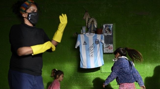 Replika jersey timnas Argentina yang dipakai di final Piala Dunia 1986 dengan tanda tangan Diego Maradona tergantung di tembok kantin komunitas di Jose C. Paz, Buenos Aires, Argentina di kala lockdown diberlakukan untuk mencegah penyebaran virus corona. (8/5/2020) (AFP/JUAN MABROMATA)