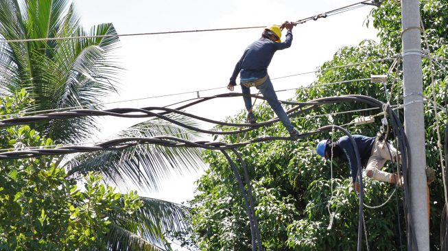 Pekerja memasang kabel empetik milik PT PLN Persero di jalur aliran penghubung tiga kabupaten, Kendari, Sulawesi Tenggara, Minggu (10/5).  [ANTARA FOTO/Jojon]