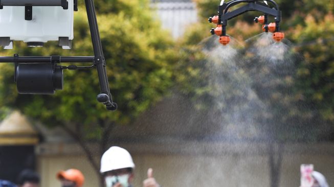 Sebuah pesawat nirawak atau drone menyemprotkan cairan disinfektan di kawasan Pancoran, Jakarta, Senin (11/5).  [ANTARA FOTO/Hafidz Mubarak ]
