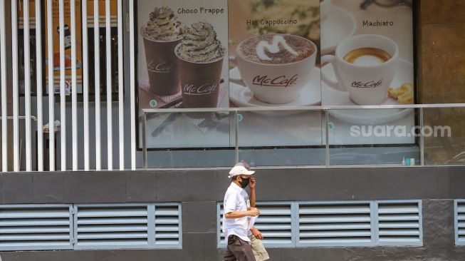 Warga melintas didepan Mcd Sarinah, Jakarta Pusat, Senin (11/5). [Suara.com/Alfian Winanto]