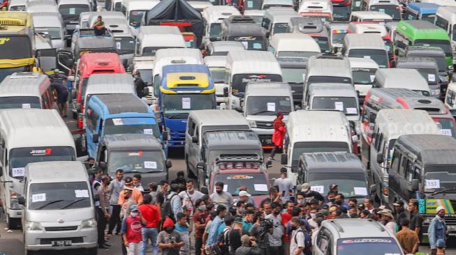 Ratusan kendaraan travel gelap yang mengangkut pemudik  di lapangan promoter Polda Metro Jaya, Jakarta Pusat, Senin (11/5). [Suara.com/Alfian Winanto]