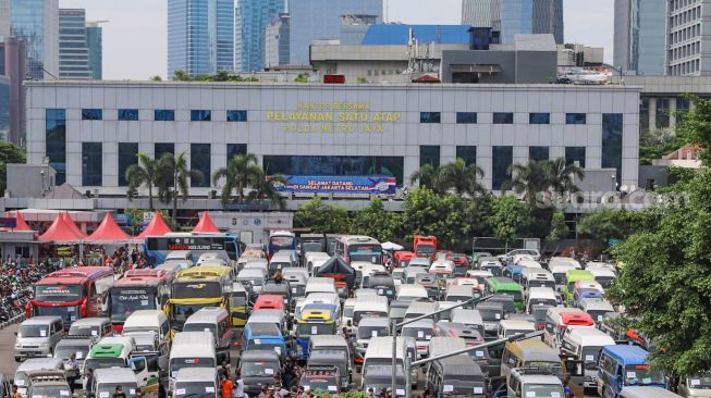 Ratusan kendaraan travel gelap yang mengangkut pemudik  di lapangan promoter Polda Metro Jaya, Jakarta Pusat, Senin (11/5). [Suara.com/Alfian Winanto]
