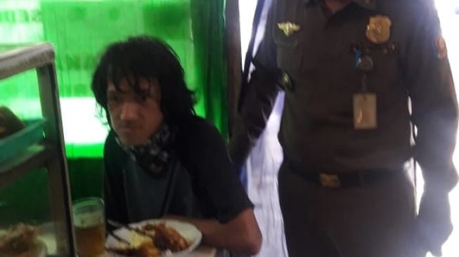 Seorang pria bernama Mulyadi (23) saat makan di warteg setelah ditemukan tergeletak dalam posisi sujud di sekitar Mall Gandaria City, Kebayoran Lama, Jakarta Selatan. (Ist)