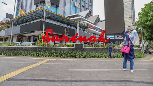 Warga berfoto didepan persimpangan Mcd Sarinah, Jakarta Pusat, Senin (11/5). [Suara.com/Alfian Winanto]
