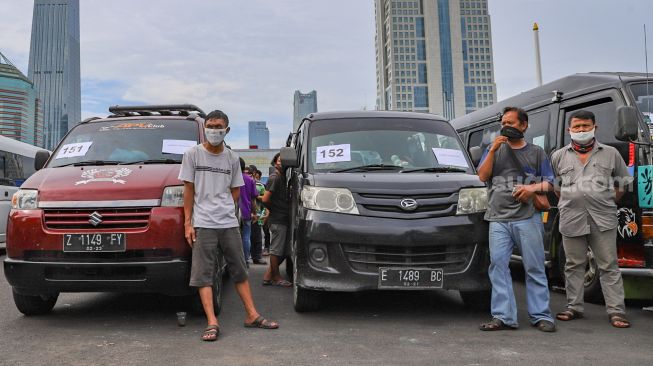 Pengemudi travel didepan kendaraannya di lapangan promoter Polda Metro Jaya, Jakarta Pusat, Senin (11/5). [Suara.com/Alfian Winanto]