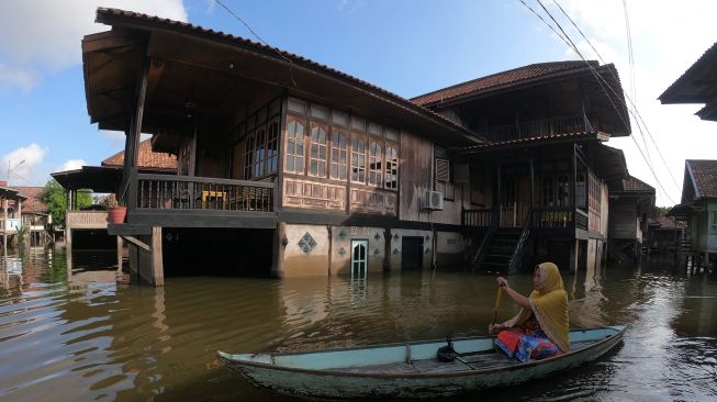 Warga menggunakan perahu melintasi permukiman yang terendam banjir luapan Sungai Batanghari di Mudung Laut, Pelayangan, Jambi, Selasa (12/5).  [ANTARA FOTO/Wahdi Septiawan]