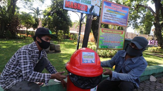 Pekerja memasang tempat sampah khusus untuk membuang masker bekas di pinggir jalan arteri di Kota Kediri, Jawa Timur, Selasa (12/5).  [ANTARA FOTO/Prasetia Fauzani]