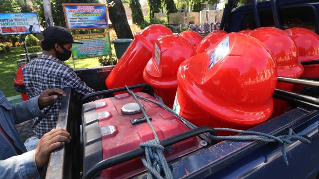 Pekerja bersiap memasang tempat sampah khusus untuk membuang masker bekas di pinggir jalan arteri di Kota Kediri, Jawa Timur, Selasa (12/5).  [ANTARA FOTO/Prasetia Fauzani]
