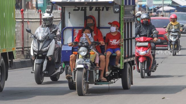 Pengendara sepeda motor membawa penumpang di kawasan Kramat Jati, Jakarta Timur, Rabu (13/5). [Suara.com/Alfian Winanto]