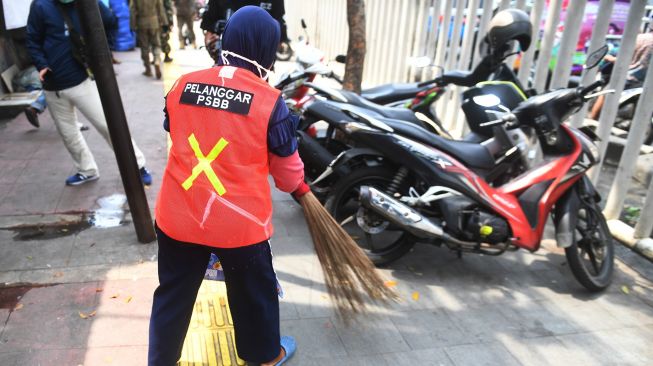 Warga yang terjaring razia penindakan pelanggaran aturan Pembatasan Sosial Berskala Besar (PSBB) oleh Satpol PP menjalani hukuman dengan cara membersihkan sampah di Tanah Abang, Jakarta, Rabu (13/5).  [ANTARA FOTO/Akbar Nugroho Gumay]