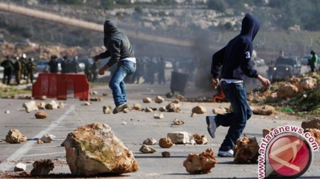 Pemuda Palestina melemparkan batu ke arah pasukan keamanan Israel dalam bentrokan di depan penjara Ofer dekat kota Tepi Barat, Ramallah, Senin (13/2). (ANTARA/REUTERS/Mohamad Torokman) 