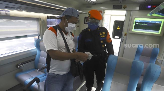 Petugas memeriksa tiket seorang calon penumpang di dalam gerbong Kereta Api Luar Biasa jurusan Gambir-Surabaya Pasar Turi yang berangkat dari Stasiun Gambir, Jakarta, Rabu (13/5). [Suara.com/Angga Budhiyanto]
