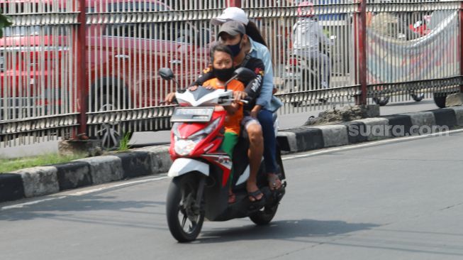 Pengendara sepeda motor membawa penumpang di kawasan Kramat Jati, Jakarta Timur, Rabu (13/5). [Suara.com/Alfian Winanto]
