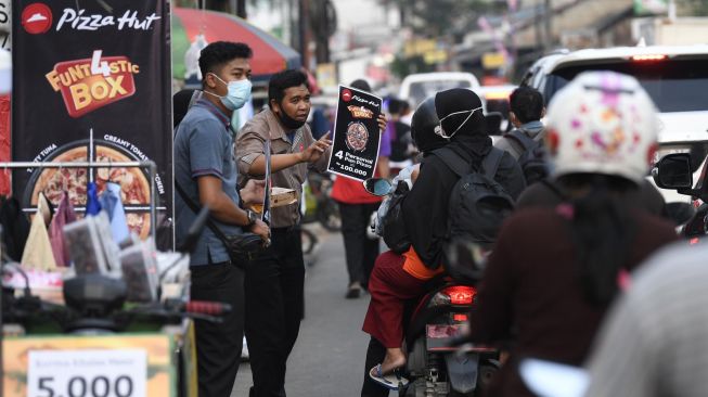 Karyawan pizza hut menawarkan produk kepada warga yang melintas di Pondok Betung, Tangerang Selatan, Banten, Rabu (13/5).  [ANTARA FOTO/Puspa Perwitasari]