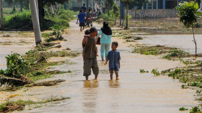 Warga berjalan melintasi banjir di Desa Gubukan Cibereum, Lebak, Banten, Kamis (14/5). [ANTARA FOTO/Muhammad Bagus Khoirunas]