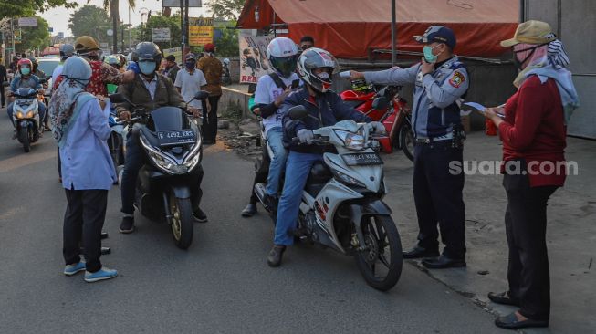 Petugas mengecek suhu tubuh pengendara sepeda motor yang akan memasuki Bekasi dengan Thermo Gun di Check Point PSBB Pondok Gede, Bekasi, Jawa Barat, Kamis (15/5). [Suara.com/Alfian Winanto]