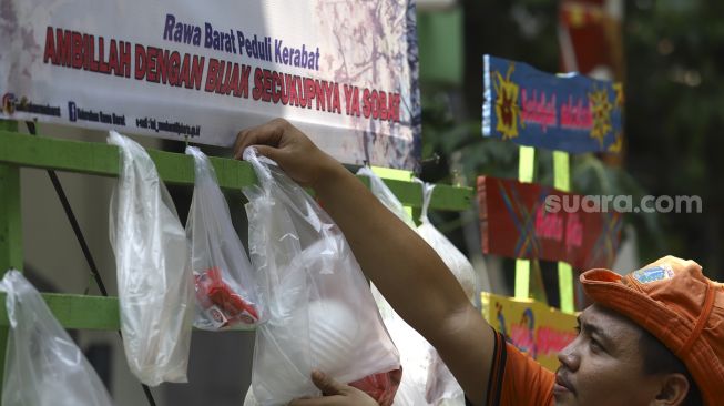 Petugas menata sembako yang digantung di rak kayu di kawasan Rawa Barat, Jakarta Selatan, Kamis (14/5). [Suara.com/Angga Budhiyanto]