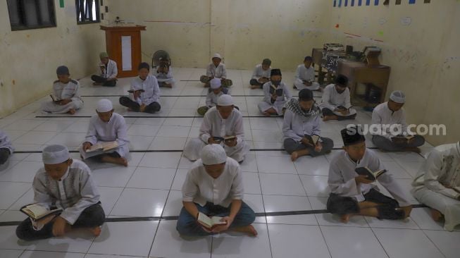 Para santri membaca Al - Quran dengan menerapkan Phsycal Distancing di Pesantren Al Kautsar Darul Quran, Bogor, Jawa Barat, Rabu (13/5). [Suara.com/Alfian Winanto]