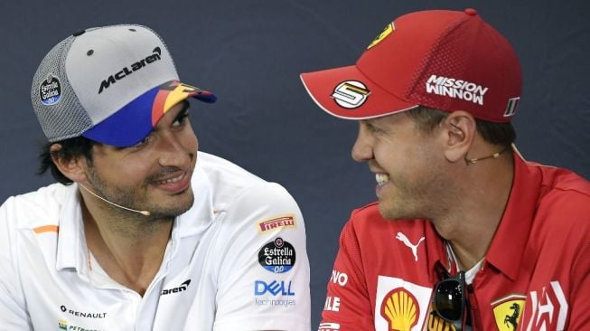 Pebalap muda Spanyol dari tim McLaren, Carlos Sainz, berbincang dengan seniornya asal Jerman yang memperkuat tim Ferrari, Sebastian Vettel, saat acara konferensi pers jelang F1 GP Barcelona, Kamis (9/5/2019). [AFP/Lluis Gene]