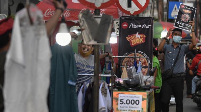 Karyawan pizza hut menawarkan produk kepada warga yang melintas di Pondok Betung, Tangerang Selatan, Banten, Rabu (13/5).  [ANTARA FOTO/Puspa Perwitasari]