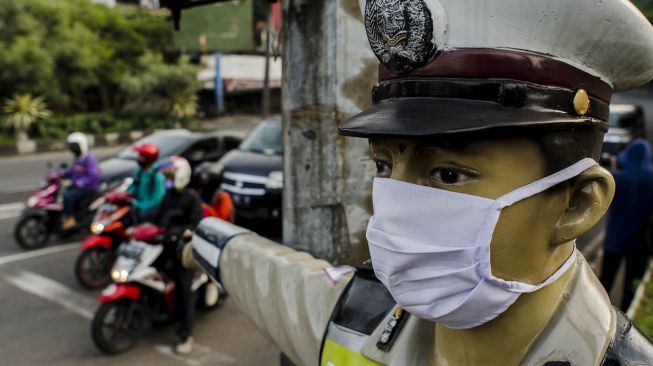 Patung polisi lalu lintas yang terletak di ruas jalan dipasangkan masker di Bandung, Jawa barat, Jumat (15/5).  [ANTARA FOTO/Novrian Arbi]