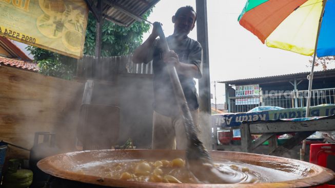 Pekerja mengaduk adonan dodol yang dimasak agar tidak mengeras di Sentra Dodol  Zakiyah, Pejaten Timur, Pasar Minggu, Jakarta Selatan, Jumat (15/5).  [Suara.com/Alfian Winanto]
