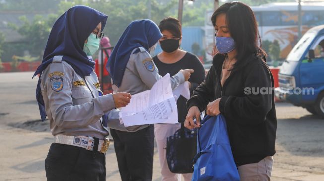 Petugas memeriksa surat tugas kantor para penumpang yang akan bekerja menggunakan transportasi Kereta Rel Listrik (KRL) di Stasiun Depok Baru, Depok, Jawa Barat, Jumat (15/5). [Suara.com/Alfian Winanto]