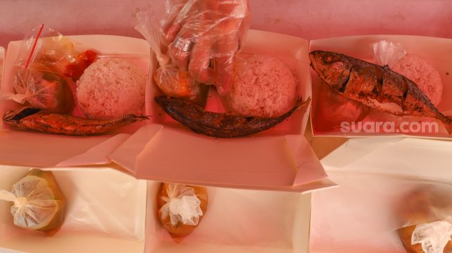 Warga menata makanan dan lauk pauk untuk dibungkus  di Dapur Umum Kasih Bayangkari Peduli Polda Metro Jaya, Tanah Abang, Jakarta Pusat, Sabtu (16/5). [Suara.com/Alfian Winanto]