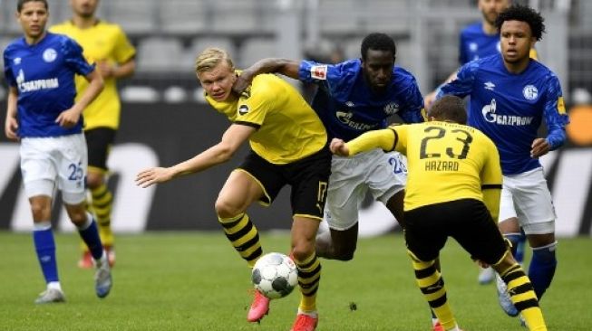 Pemain Schalke 04 mencoba menghentikan laju pemain Borussia Dortmund Erling Haaland dalam pertandingan Bundesliga di Signal Iduna Park, Sabtu (16/5/2020). [AFP]